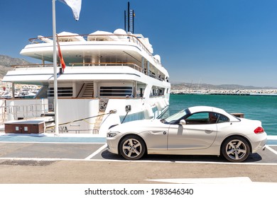 Marbella, SPAIN - July 16 2020: Luxury Puerto Jose Banus Harbour situated in Nueva Andalucia area of Marbella city. Expensive yacht docked, white BMW parked near. Luxury lifestyle on Costa del Sol