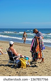 MARBELLA, SPAIN - SEPTEMBER 12, 2008 - Beach Trader Showing His Goods To A Tourist On Playa De La Vibora Beach, Elviria, Marbella, Malaga Province, Andalusia, Spain, September 12, 2008.