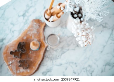 A marble countertop features holiday baking tools, cookie cutters, and decorative winter accents. The scene captures a warm, inviting atmosphere perfect for festive culinary creations. - Powered by Shutterstock