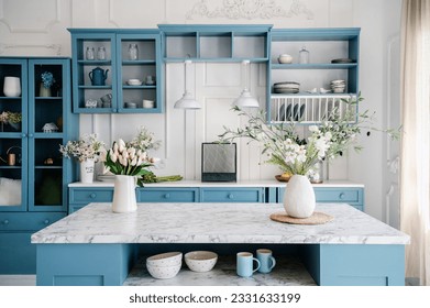 Marble countertop with vases and flowers in provence style apartment. Kitchen island and dining table with tableware. Blue furniture and white walls in classic interior design room. - Powered by Shutterstock