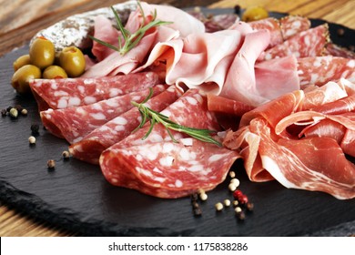 Carte de découpe en marbre avec prosciutto, bacon, salami et saucisses sur fond bois. Plateau de viande