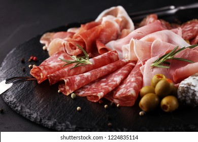Marble cutting board with prosciutto, bacon, salami and sausages on wooden background. Meat platter - Shutterstock ID 1224835114