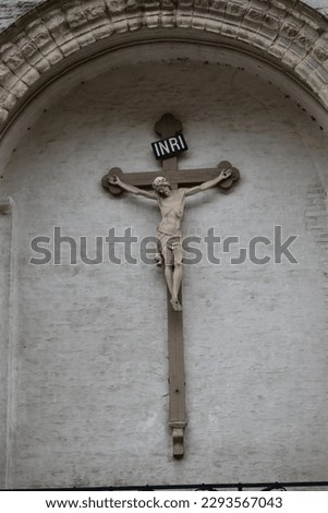 A marble Jesus Christ on a wooden cross with the letters 