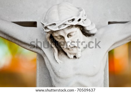 Marble statue of the crucifixion of Jesus with a colorful out of focus background