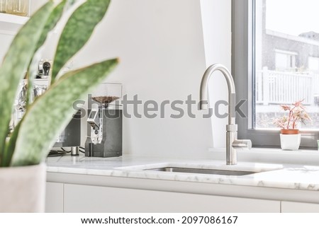 Marble white gray countertop with faucet and sink near the window