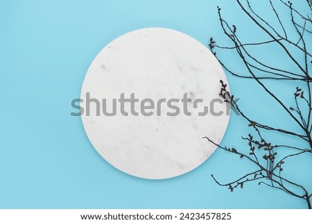 Marble white podium with burgeoning branch on blue background. Copy space simple pastel rustic background for traditional Easter holiday card