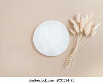 Marble white round podium and bouquet of dry Lagurus on beige background. Place, background for cosmetics. Top view. Copy space - Shutterstock ID 2031314498