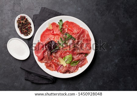 Marbled beef carpaccio with arugula, lemon and parmesan cheese. Top view, flat lay with copy space