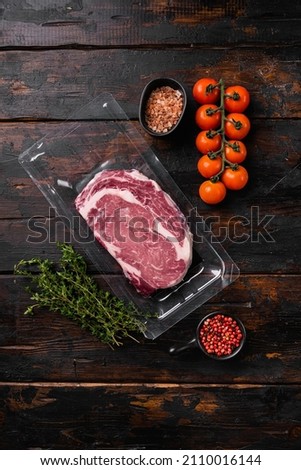 Marbled beef from the store set, on old dark  wooden table background, top view flat lay, with copy space for text