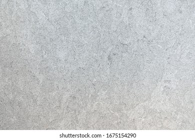 Marbled pattern of a smooth light gray stone slab in closeup