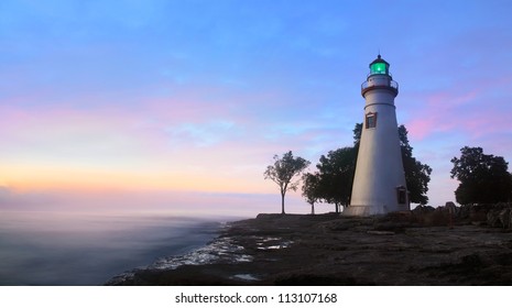 The Marblehead Lighthouse Radiates It's Green Light As The Sun Warms The Eastern Sky Initiating A Brand New Day At Marblehead Ohio On Lake Erie, USA