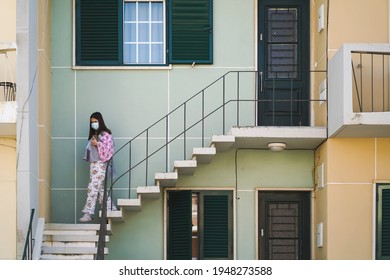 March 10, 2021 - Faro, Portugal:  Young Woman Leaving Her House Wearing Pajama And Mask During Lockdown Due To Covid 19 Pandemic