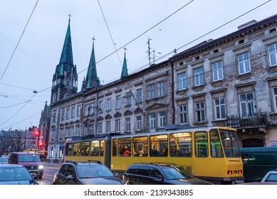 March 11, 2022, Lviv, Ukraine. Tram Of Lviv Public Transport Is Seen In The Traffic In The City Center With Monument And Church In The Background