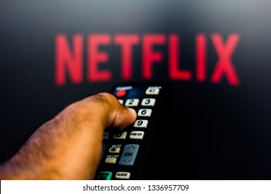 March 12, 2019, Brazil. Man with TV remote control in hand and Netflix logo in background. Netflix is ​​the global provider of streaming movies and TV series.