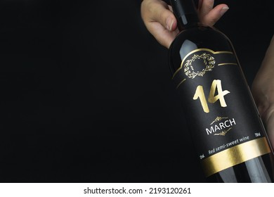 March 14th. Day 14 of month, Calendar date. Hands hold bottle of red wine with a calendar date on label.  Spring month, day of the year concept