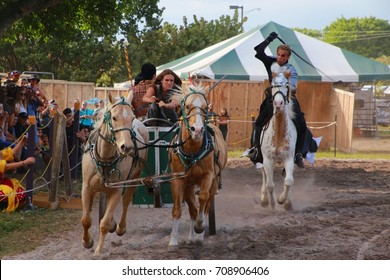 MARCH 18 2017 - RENAISSANCE FESTIVAL - DEERFIELD BEACH, FL  A Warrior Riding Horseback With A Whip Chases Other Warriors In A Horse And Carriage In Front Of Spectators.