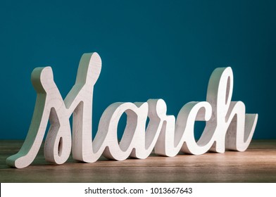 March - 1st Month Of Spring. Wooden Carved Word At Dark Blue Background. Card For Mothers Day, 8 March, Easter