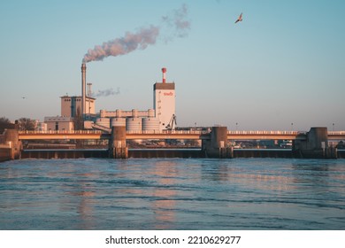 March 2 2022, Weserwehr(Bremen), Germany - River Dam (weir) Of A Hydro Power Plant Along Weser River. Water Cascading Down A Barrage.  Energy Concept. SWB Power Plant In The Background In Evening Sun.