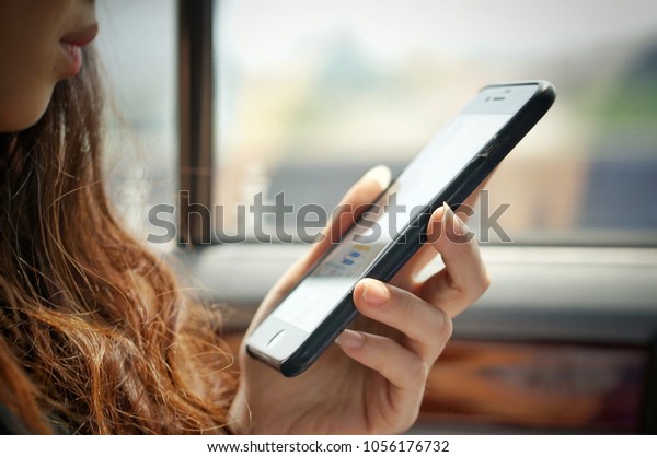 March, 2018:Unidentified woman\
watching mobile phone for work on the car at Bangkok Thailand\

