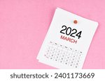 March 2024 calendar page and wooden push pin on pink Color background.