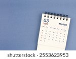 March 2025 Mini monthly desk calendar for 2025 year on blue color background, Flat Lay.