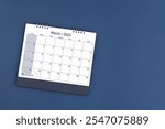 March 2025 Monthly desk calendar for 2025 year on blue color background, Position with copy space. Flat Lay.