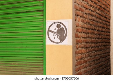 March 25, 2020. Kathmandu, Nepal. The Bouda area. The black-and-white “no spitting” sign printed on office paper is pasted on the wall of the store, by a window closed by rolling shutters. - Shutterstock ID 1705057306