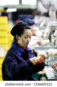 March 30, 2018: A Beautiful Young Girl Operates A Machine In The Workshop Production Line, Winding A Copper Wire To Make A Small Engine. A Sweaty Electronics Factory In Jiujiang, East China's Jiangxi.