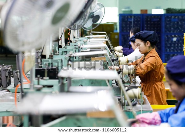 March 30, 2018: a beautiful young girl operates\
a machine in the workshop production line, winding a copper wire to\
make a small engine. A sweaty electronics factory in Jiujiang, East\
China\'s Jiangxi.