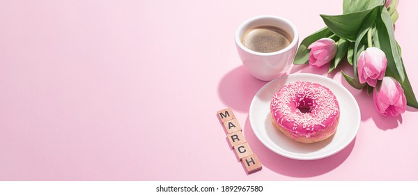 March 8, International Women's Day. number eight, consisting of a cup of coffee and a donut with a pink filling, next to pink tulips on a pink background. space for text - Powered by Shutterstock