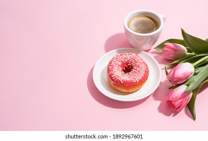 March 8, International Women's Day. number eight, consisting of a cup of coffee and a donut with a pink filling, next to pink tulips on a pink background. space for text - Powered by Shutterstock