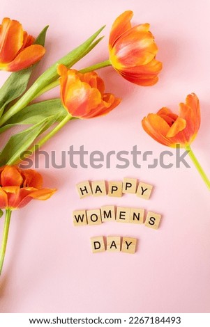 March 8, postcard. Happy Women's Day text sign on orange tulips background. Selective focus, noise. Stylish flat lay with flowers and text, greeting card
