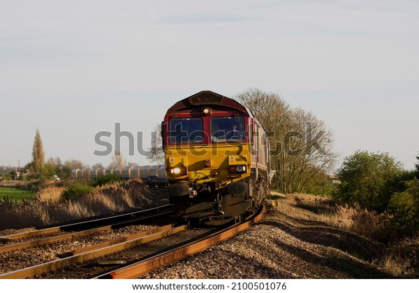 MARCH, CAMBRIDGESHIRE, UK - APRIL 6, 2011: EWS\
liveried DBS Class 66 No. 66172 ‘Paul Melleney’ rounds the curve at\
the Silt Drove crossing near March, working the 4M86 Ely Potter\
Group to Peak Forest.
