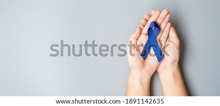 March Colorectal Cancer Awareness month, Man holding dark Blue Ribbon for supporting people living and illness. Healthcare, hope and World cancer day concept