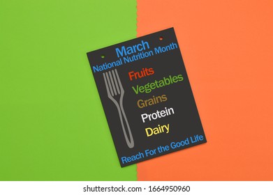 March National Nutrition Month Reach For The Good Life (Fruits, Vegetables, Grain, Protein, Dairy) Blackboard On Green And Orange Background