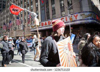 March For Our Lives: A Protester Passing Radio City Music Hall Holds A Sign In The Shape Of A Gun With A Red Flag That Says BAN At The March On 6th Ave To End Gun Violence, NEW YORK MAR 24 2018.