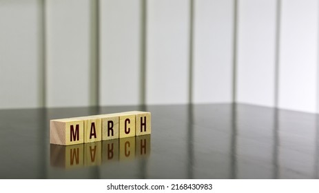 MARCH Word On Wooden Cube On Black Gloss Wooden Table. Selected Focus