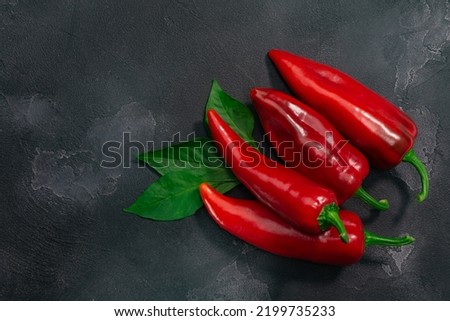 Marconi peppers atop black textured backdrop, top view, copy space. Capsicum annuum fruits