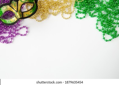 Mardi gras background on white with mask and purple gold green beads and copy space.