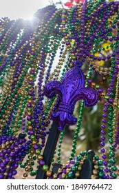Mardi Gras beads covering wrought iron fence with fleur de lis