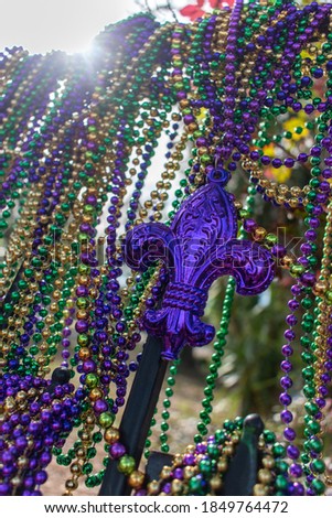 Mardi Gras beads covering wrought iron fence with fleur de lis