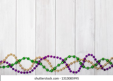 Mardi Gras beads on white wooden backgound