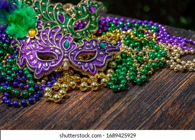 Mardi Gras Color Beads With Masks On Wooden Table In Sunlight