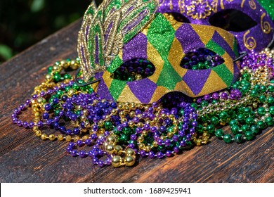 Mardi Gras Color Beads With Masks On Wooden Table In Sunlight