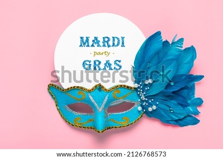 Mardi gras lettering. Congratulation card with blue mask on white podium on pink background Top view 2022 Mardi Gras Parade Schedule