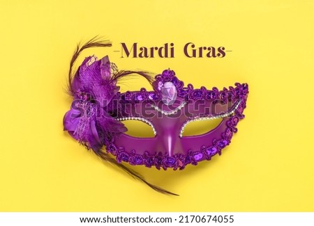 Mardi gras lettering. Congratulation card with violet mask on yellow background Top view 2022 Mardi Gras Parade Schedule Mockup Copy space.