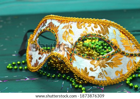 Mardi gras mask and beads on a wooden background. Madi Gras carnival accessories, confetti, Festive, venetian or carnivale mask. Masquerade celebration concept
