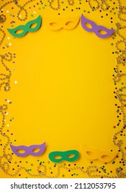 Mardi Gras Masquerade festival carnival masks, gold color beads and golden, green, purple confetti on yellow background. Party invitation, greeting card, venetian carnival celebration concept