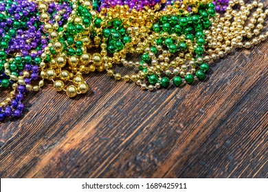 Mardi Gras Purple, Green, And Gold Beads On Wooden Table With Copy Space