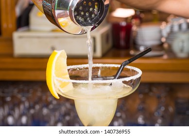 A Margarita Being Poured From The Shaker Against The Background Of The Bar